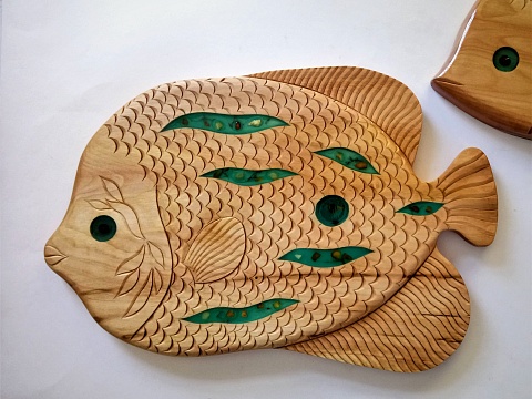 Доска выполнена из липы в форме рыбы, декорирована проско-рельефной резьбой и элементами с художественной эпоксидной смолой
